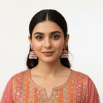 Vibrant hand-painted jhumka earrings featuring pink butterflies and orange floral patterns on a model
