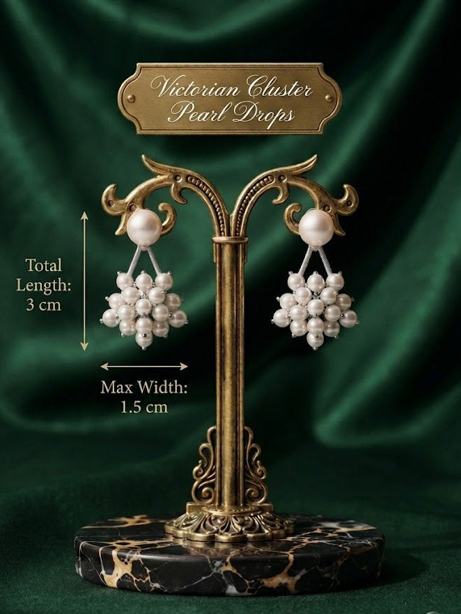 A pair of Victorian cluster pearl drops earrings displayed on an ornate gold stand with a dark green satin background. White text on the image indicates the total length is 3 cm and the maximum width is 1.