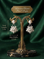 A pair of Victorian cluster pearl drops earrings displayed on an ornate gold stand with a dark green satin background. White text on the image indicates the total length is 3 cm and the maximum width is 1.