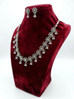 Oxidized silver sunflower-style jewelry set with clear crystal centers and triple-bead ghungroo drops displayed on a red velvet mannequin stand.