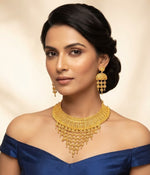 Posh model wearing the Wareesha heritage filigree micro gold-plated statement necklace and earring set by Famaza Couture on a plain background.