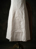 White cotton gharara featuring intricate traditional bakhiya embroidery, wide flared design, displayed on stand.