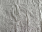 White embroidered cotton fabric with detailed floral and paisley patterns and a decorative border.