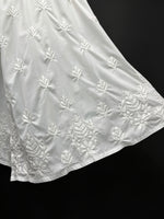 White embroidered fabric with floral patterns on a black background