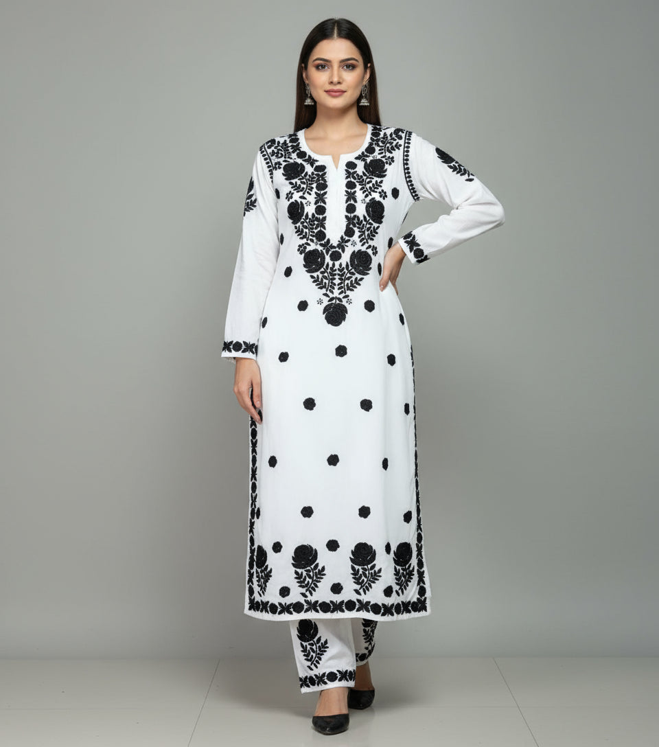 White outfit with black floral embroidery on a light gray background