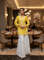 Mannequin wearing a yellow dress with white floral pattern on a grey floor.