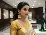 Woman in a gold saree with jewellery display in the background