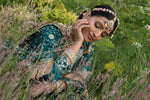 Woman in traditional attire among flowers and greenery