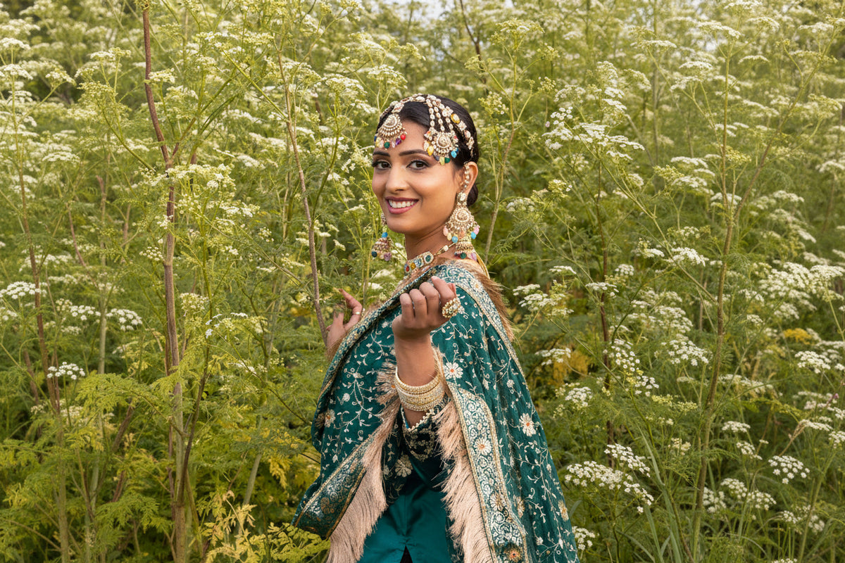 Woman in traditional attire standing among trees with white flowers