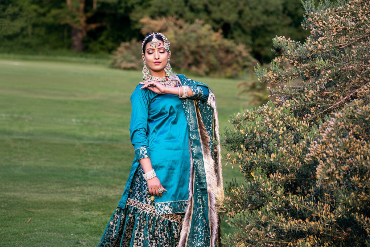 Woman in traditional attire standing outdoors with greenery in the background