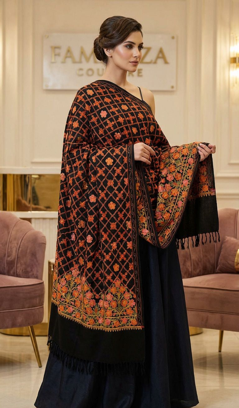 Woman wearing a black and orange patterned shawl in an elegant room.