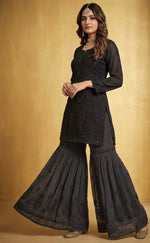 Woman wearing a beige top and black flared hand embroidered gharara pants 