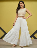 Woman wearing a beige top and white flared hand embroidered gharara pants 