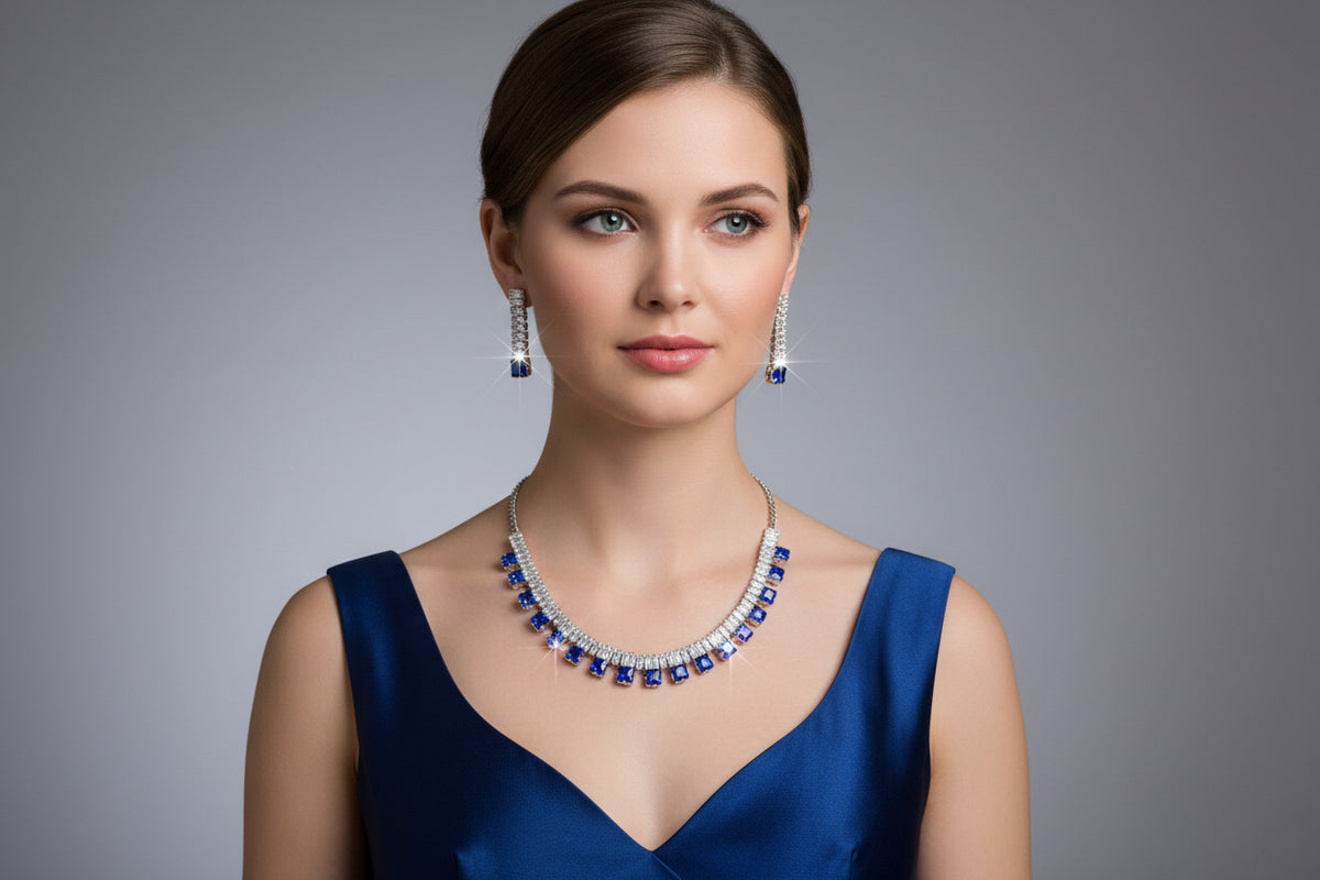 Woman wearing a blue dress with a matching necklace and earrings against a gray background