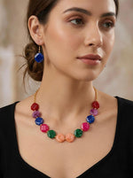 Woman wearing a colorful beaded necklace and earrings against a neutral background