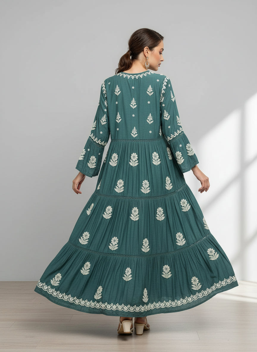 Woman wearing a green colour dress with white floral patterns in a neutral setting.