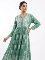Woman wearing a green dress with white floral patterns on a white background