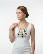 Woman wearing a long, multi-layered necklace with various colored stones on a white background