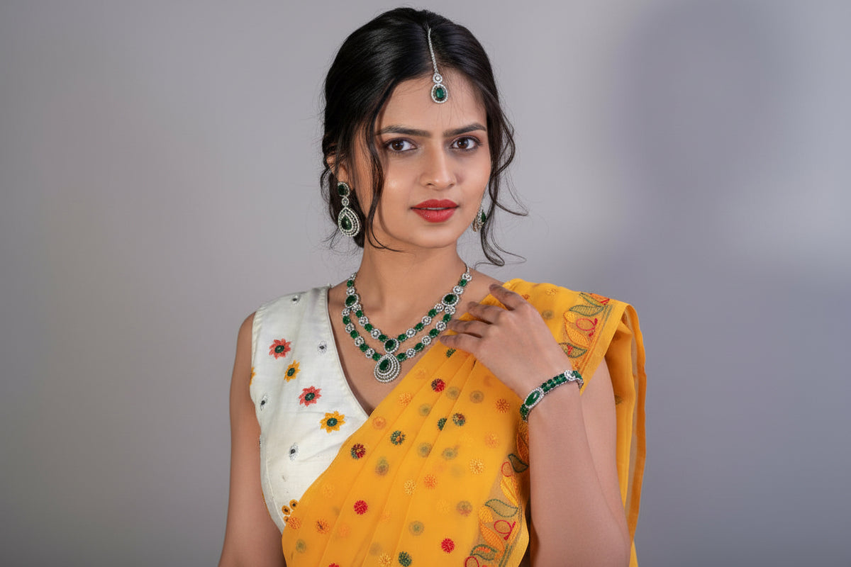 Woman wearing a mango yellow saree with floral patterns and a yellow dupatta, holding the dupatta against a grey background.