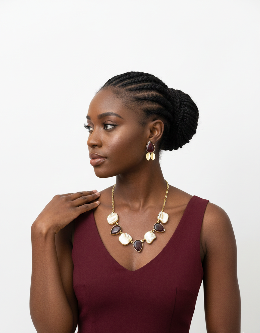 Woman wearing a maroon dress with a gold necklace and earrings on a white background