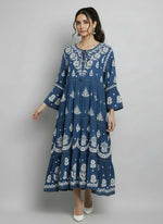 Woman wearing a navy blue colour dress with white floral patterns in a neutral setting.