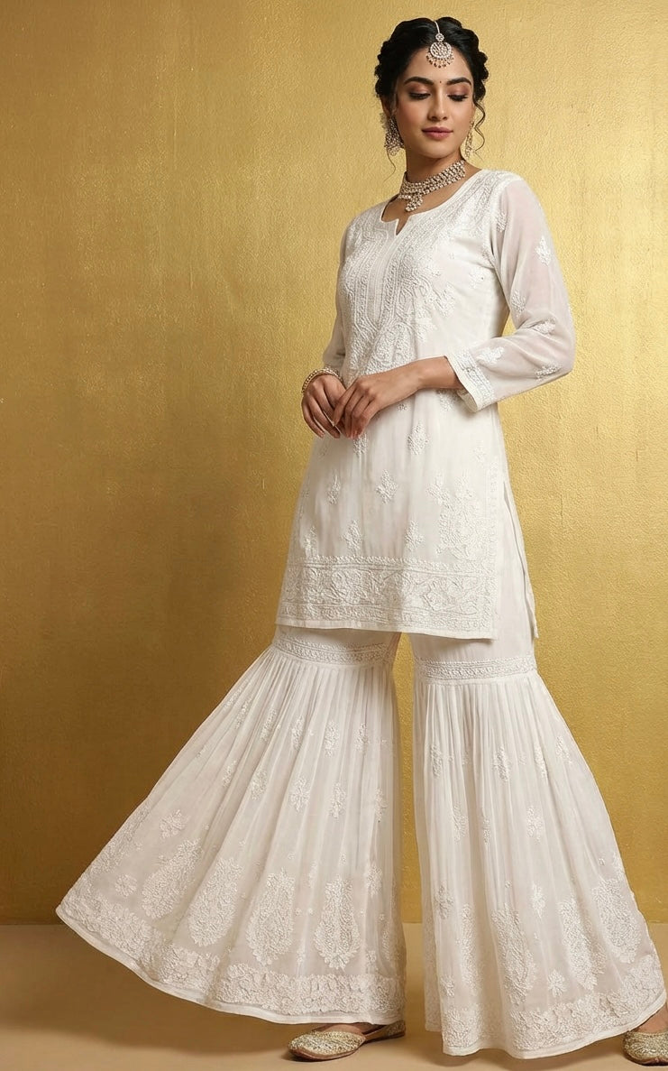 Woman wearing a whitetop and white flared hand embroidered gharara trousers 