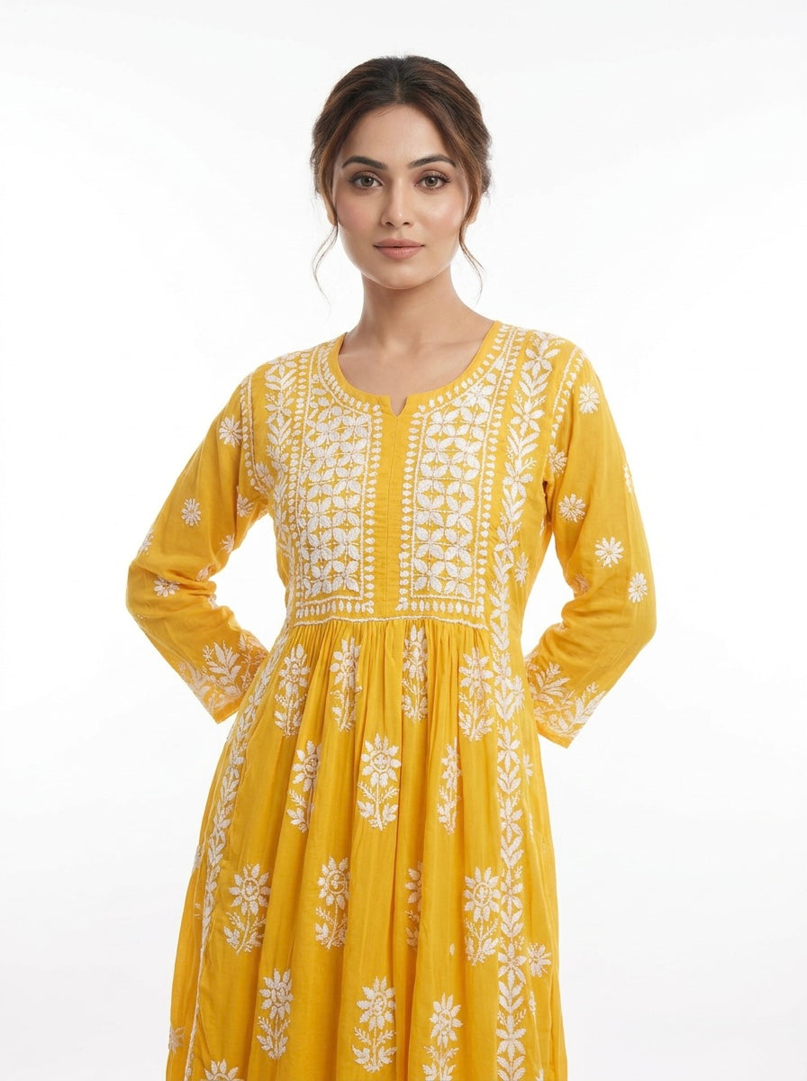 Woman wearing a yellow dress with white floral embroidery on a white background
