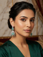 Woman wearing green earrings with a blurred background