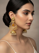 Woman wearing rose gold earrings with a neutral background