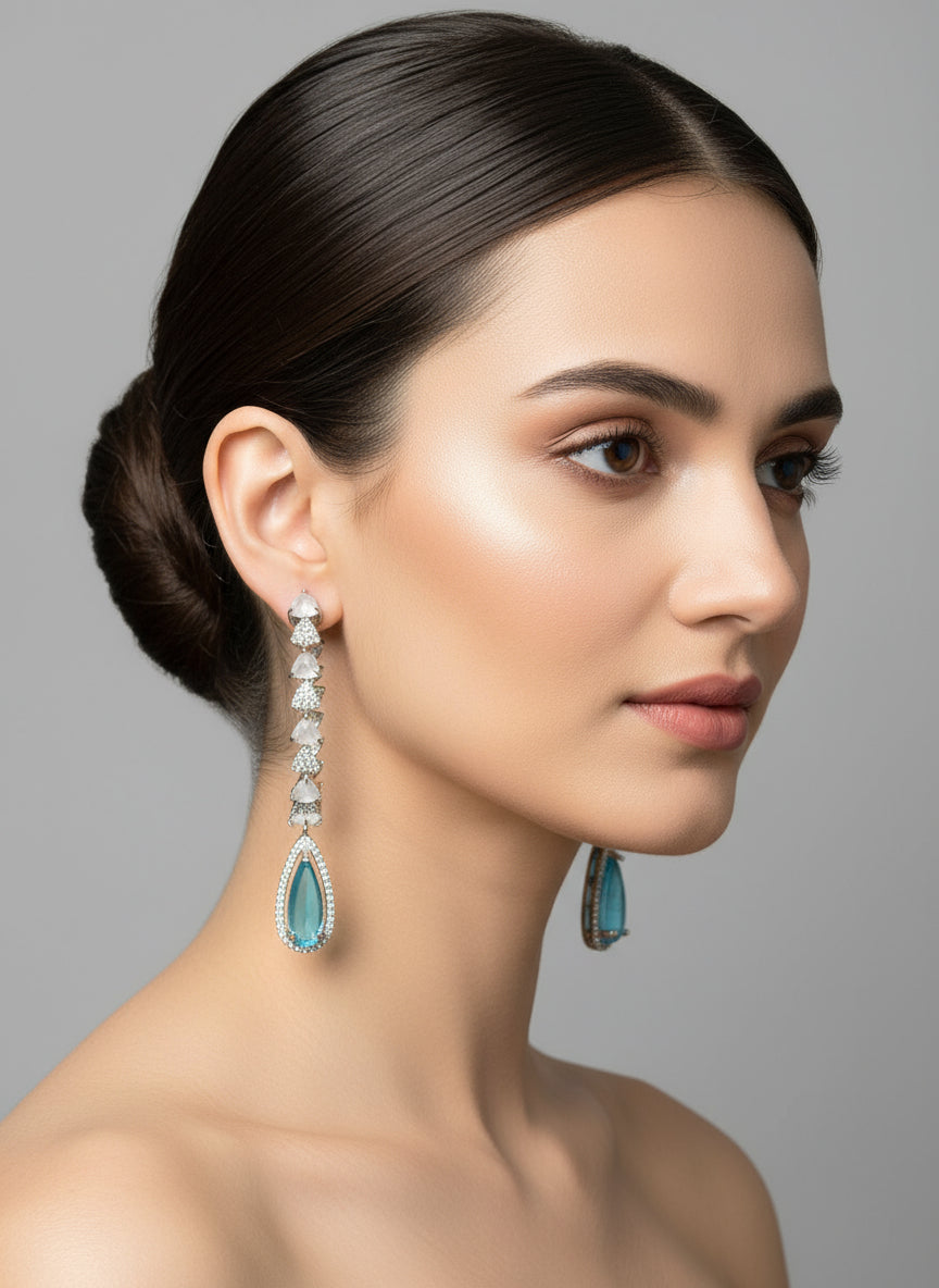 Woman wearing turquoise teardrop earrings against a gray background