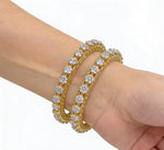 Pair of gold-plated bangles featuring a delicate honeycomb lattice design adorned with floral-shaped American Diamond clusters, shown on a model's wrist with a clean white background.
