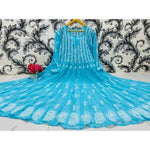Blue embroidered dress on a hanger against a decorative wall.