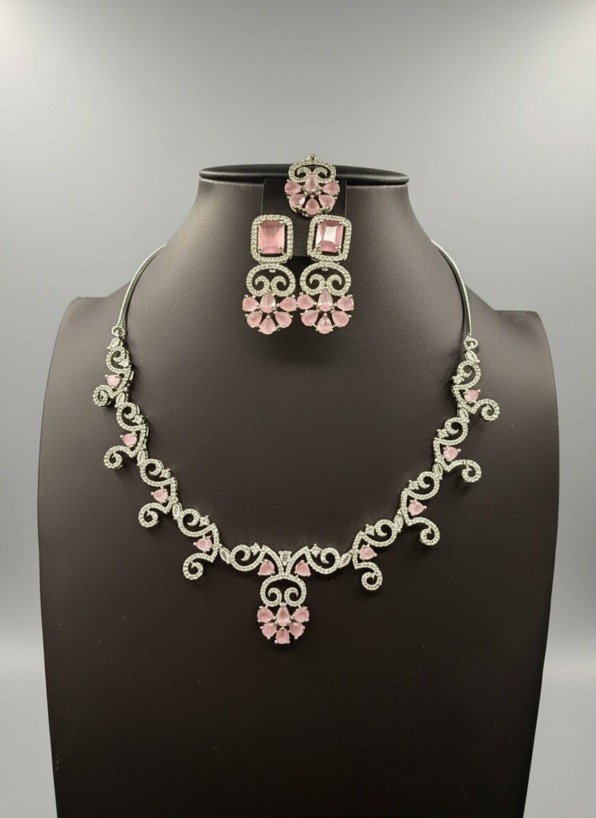 a set of AD (Artificial Diamond) jewellery which includes a necklace, earrings, and a maang tikka with pink centre stones by famaza couture 