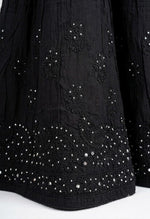 Close-up of a black cotton gharara featuring intricate antique silver kaamdani work and delicate black thread bakhiya embroidery on the flared hem.