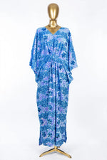 Blue Radiance floral sequin velvet kaftan on a gold mannequin, showing its long batwing sleeves and flowing silhouette
