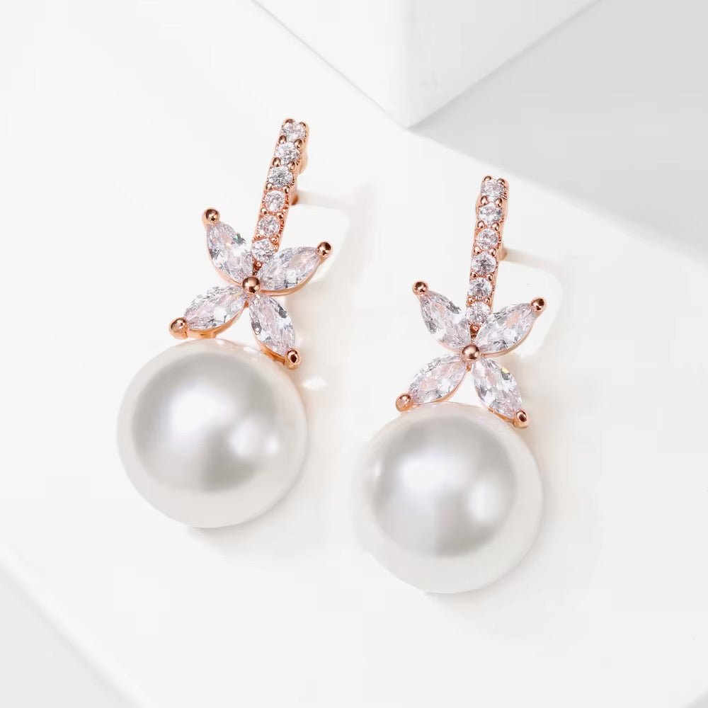 Pearl earrings with rose gold butterfly-shaped clasps on a light background