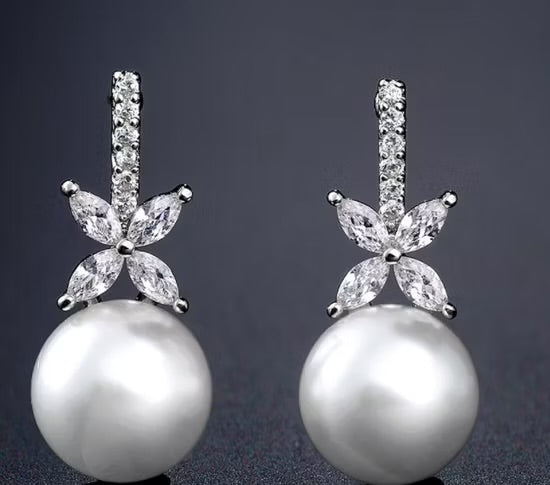 Pearl earrings with diamond-like stones on a dark background