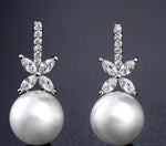 Pearl earrings with diamond-like stones on a dark background