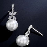 Pearl earrings with silver leaves on a dark background
