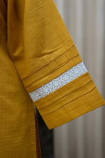 close up of mustard yellow sleeves design adorned with white lace of a kurti. 