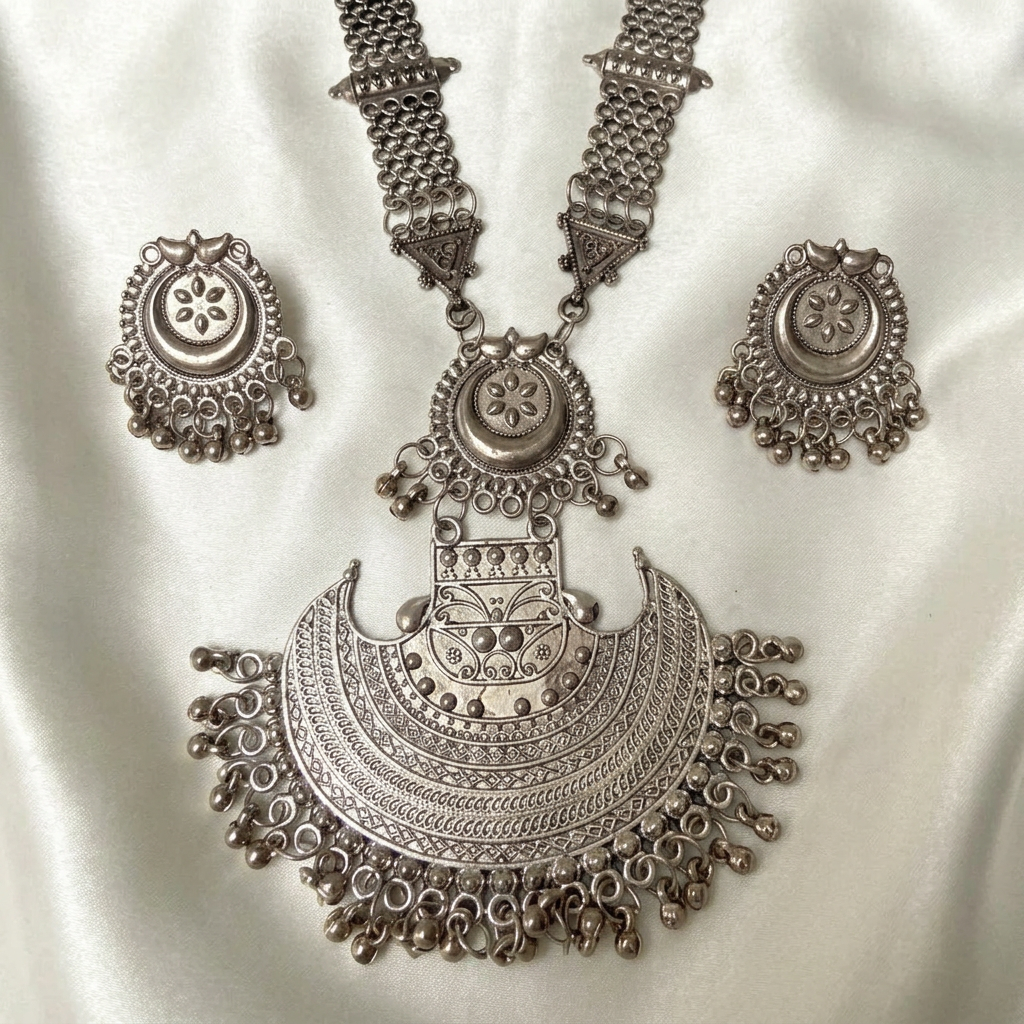 Close-up of Crescent Empress oxidised silver-tone crescent pendant and matching bead-fringed earrings on ivory silk