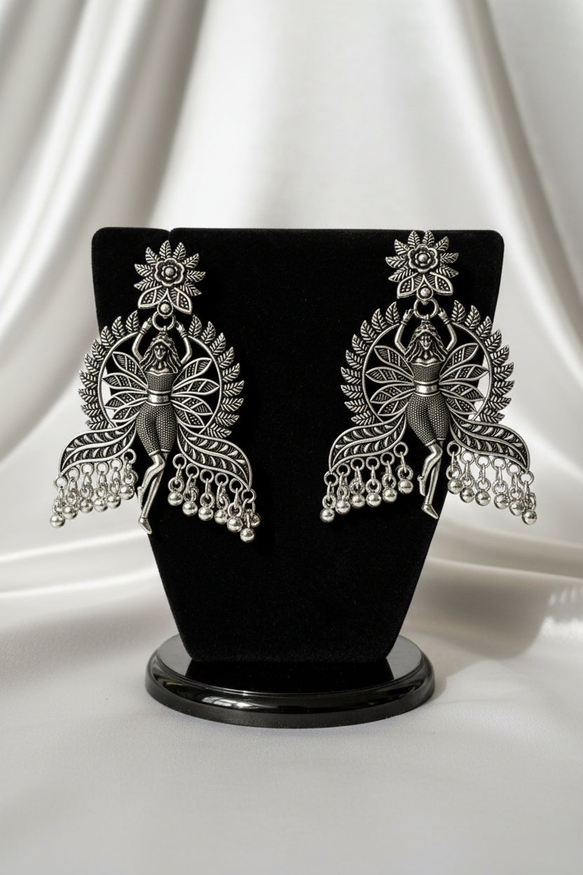 Close-up detail of antique oxidised silver polish on dancing fairy doll silhouette statement earrings