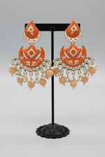 enamel painted orange colour Pair of earrings displayed on a stand. 