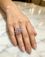 Close-up of a model wearing the Famaza Couture Royal Magenta-Pink Floral Cluster Statement Ring on a marble surface, showcasing its vibrant oval pink gemstones and silver-tone pavé crystal setting.