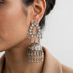 Model wearing a Raasya silver-tone teardrop jhumka earring with mirror accents, a decorative dome and dangling bead chains.