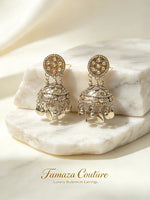 Dual-tone kundan jhumka earrings on pale stone, with antique silver-tone domes, gold-tone accents and dangling teardrop charms.