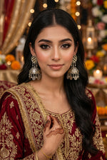 Model wearing antique silver-tone dome jhumka earrings with round stone-set tops and dangling coin charms.