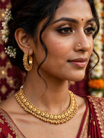 Model in a maroon embroidered outfit wearing the Gilded Grace gold-toned choker and a matching hoop earring