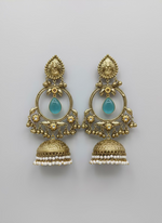Gold and turquoise stone earrings on a white card, held by a hand against a white background.