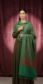 Woman wearing a green and red patterned shawl against a maroon curtain backdrop